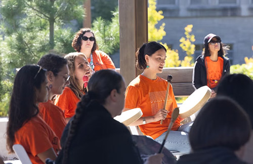 A person wearing an orange shirt drumming with other people orange shirts