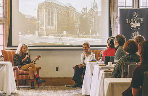 Emma Donoghue and Martha Baillie sit in a room in front of a projector screen