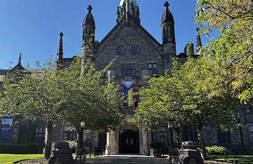 A Pride flag hangs from the entrance to Trinity College