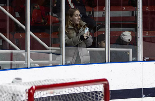 A woman look out at a hockey rink from behind the glass