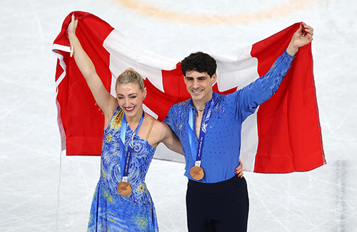 Piper Gilles and Paul Poirier hold the Canadian Flag