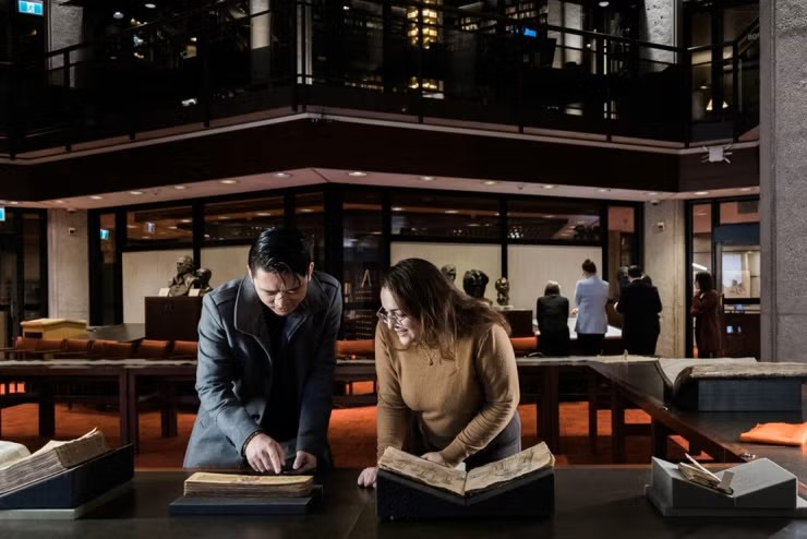 Two individuals looking at an archival book