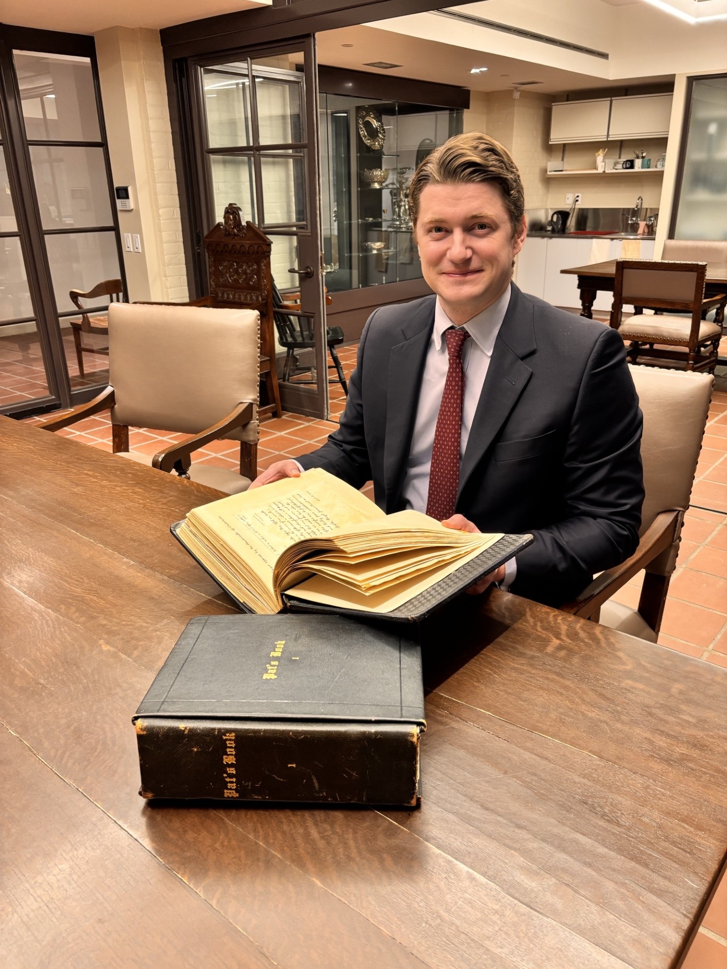 Tristan Strathy sits in the Archives with his family srapbook