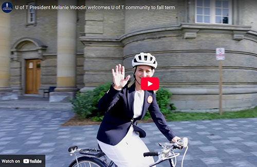 U of T President Woodin riding her bike infront of Convocation Hall