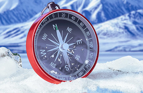 close up of a red compass in snow