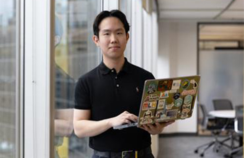 A man poses with an open laptop