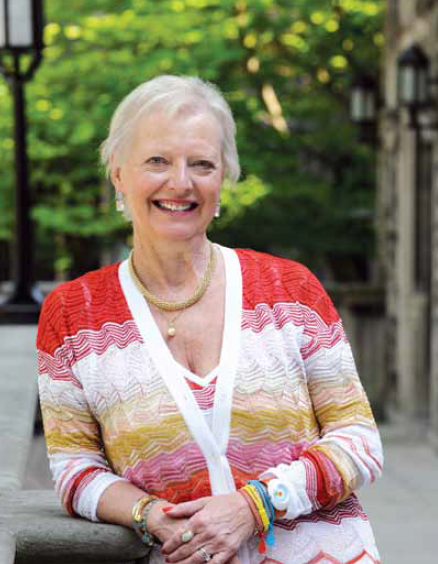 Anne Steacy wears a bright cardigan, and smiles for the camera