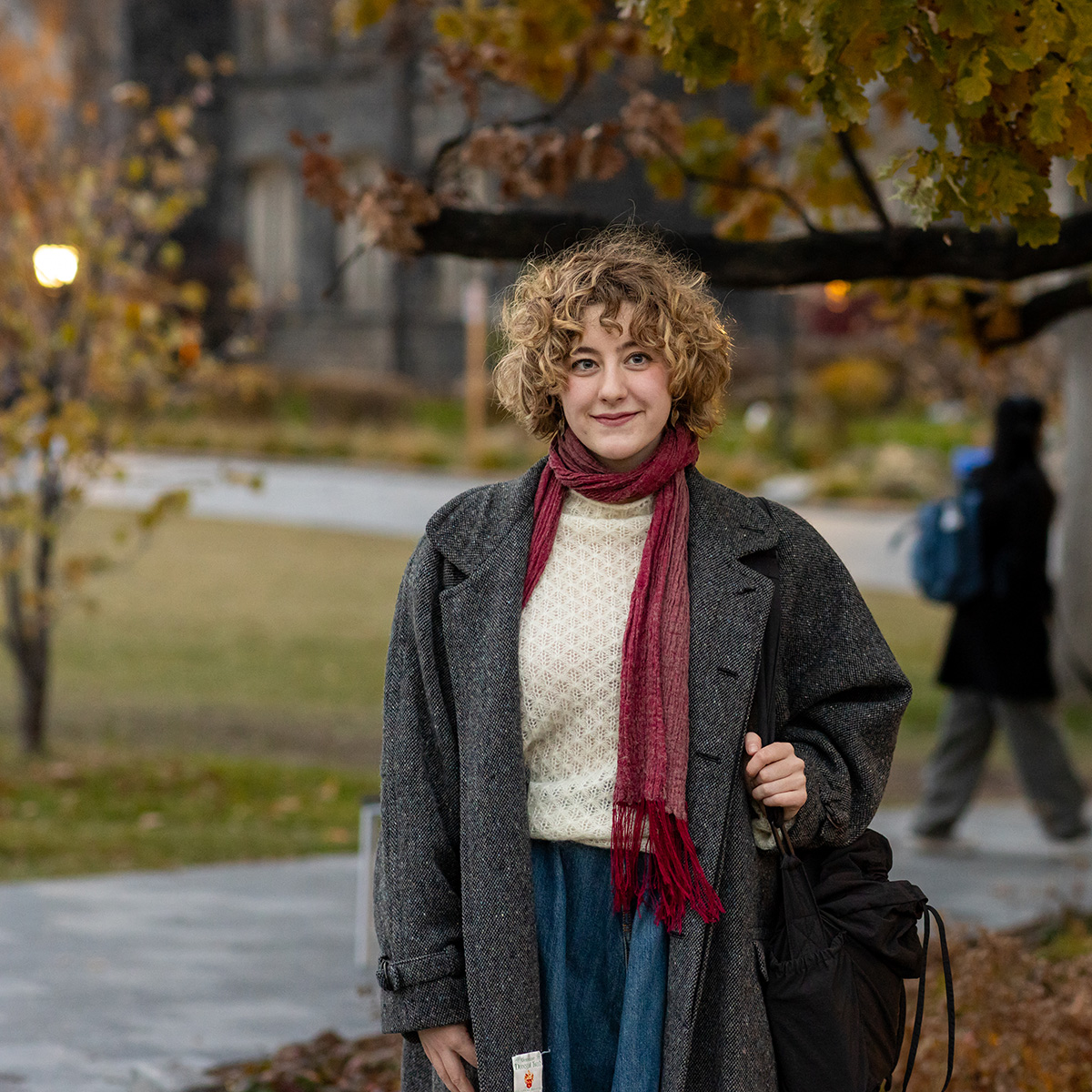 Alice Ferguson-O’Brien stands along a pathway at U of T in the fall season