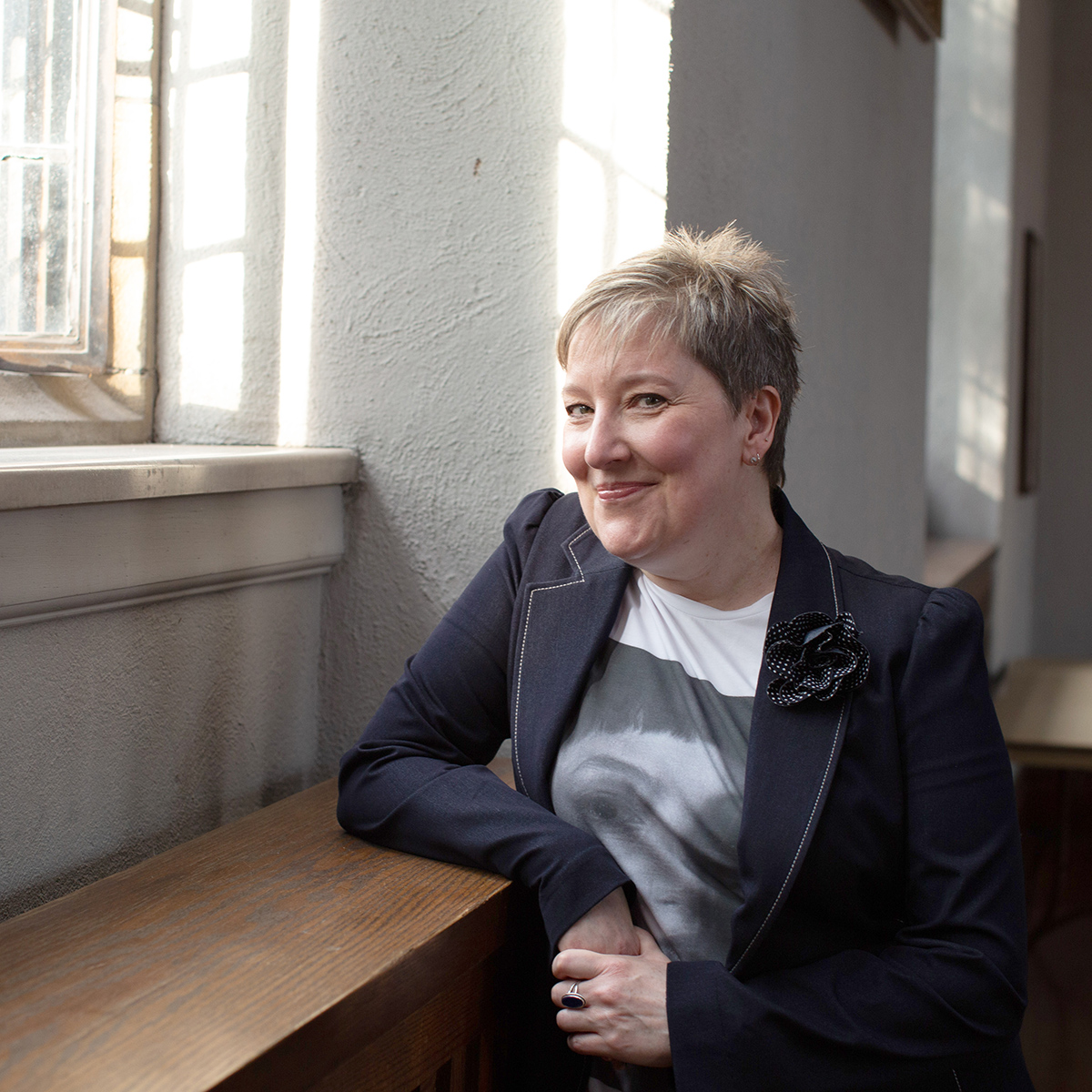 Joy Fitzgibbon stands infront of a window with sunshine streaming in